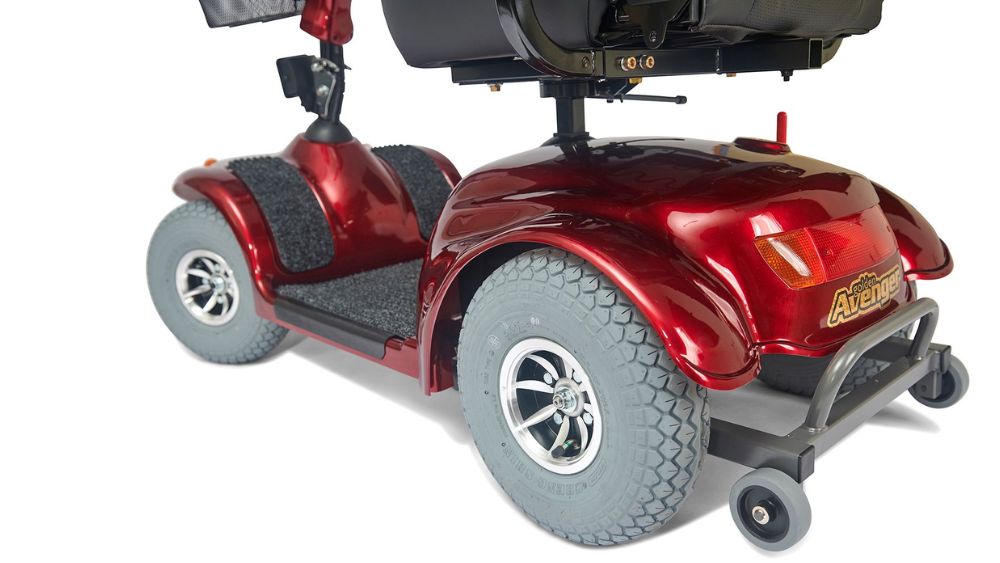 The Avenger 4-Wheel Scooter is a red mobility scooter featuring four wheels, rugged tires, a black seat, and rear safety lights, shown from a rear-side angle on a white background.
