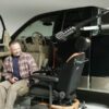 Man in turn-out transfer seat looking at power chair attached to Out Rider lift in back of pickup truck