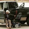 Man in turn-out transfer seat securing Out Rider lift in back bed of pickup truck to power wheelchair