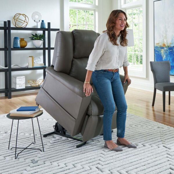 A woman stands up from a MaxiComfort Series Day Dreamer Power Lift Recliner in a bright, modern living room.
