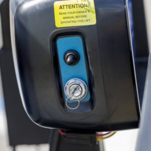 Close-up of the Harmar Universal Scooter Lift (AL100) control panel, showing a key switch with key inserted, a toggle switch, and a yellow warning label above.