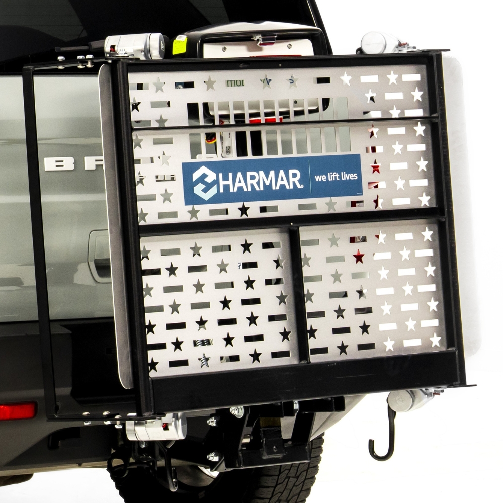 A Harmar Fusion Lift (AL300-MW) with a star-patterned metal panel is mounted on the rear of a vehicle, partially obscuring the tailgate and taillight.