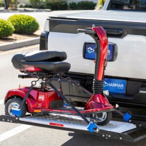 A red mobility scooter is secured on a Harmar Extra Large Fusion Lift (AL301XL) mounted to the rear of a white pickup truck in a parking lot.