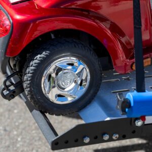 Close-up of a shiny chrome wheel on a red mobility scooter, securely fastened to the Harmar Extra Large Fusion Lift (AL301XL) platform with a blue safety strap.