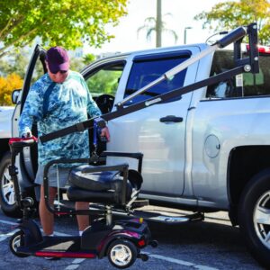 A person uses the Harmar 150 Speed Crew Cab Lift (AL815CC) attached to a pickup to load or unload a mobility scooter in a parking lot.