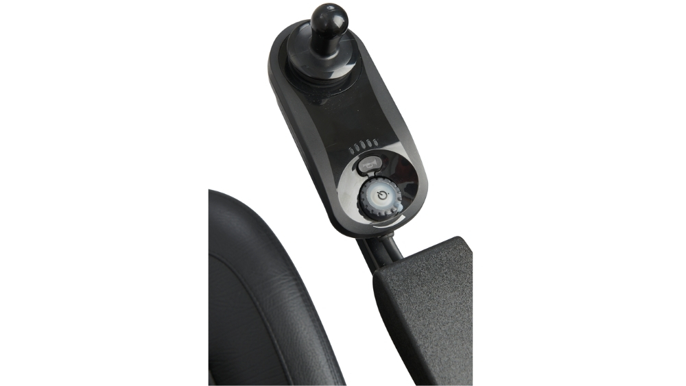 Close-up of a black joystick control panel on a Compass Sport Power Wheelchair, showing buttons, a knob, and part of the padded armrest.