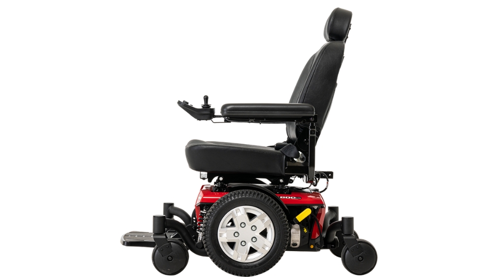 A side view of the Jazzy 600ES Power Wheelchair, featuring a red and black design, padded seat, armrests, joystick controller, and four wheels.