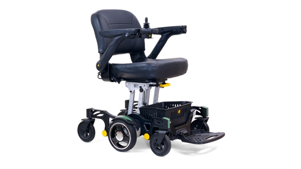 The Buzzaround CarryOn Power Wheelchair is a black carryon model featuring a padded seat, armrests, a joystick controller, and a small storage basket beneath the seat.