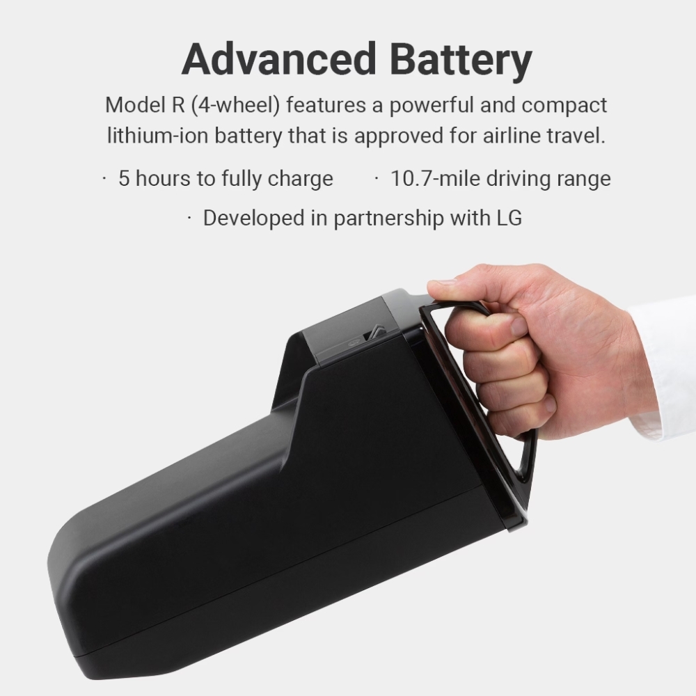 A hand holds a compact black WHILL Model R lithium-ion battery with a handle. Text above describes its 5-hour charge time, 10.7-mile range, and airline approval.