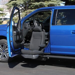 A blue pickup truck with its driver’s door open features the BraunAbility Turny Evo, which rotates and extends the driver’s seat outward for enhanced accessibility.