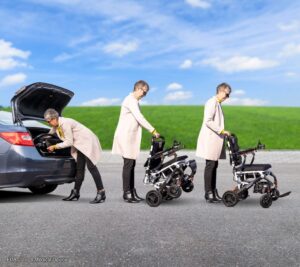 A person unfolds a Jazzy Carbon Travel Power Wheelchair by a car trunk on a sunny day, with grass and blue sky in the background.
