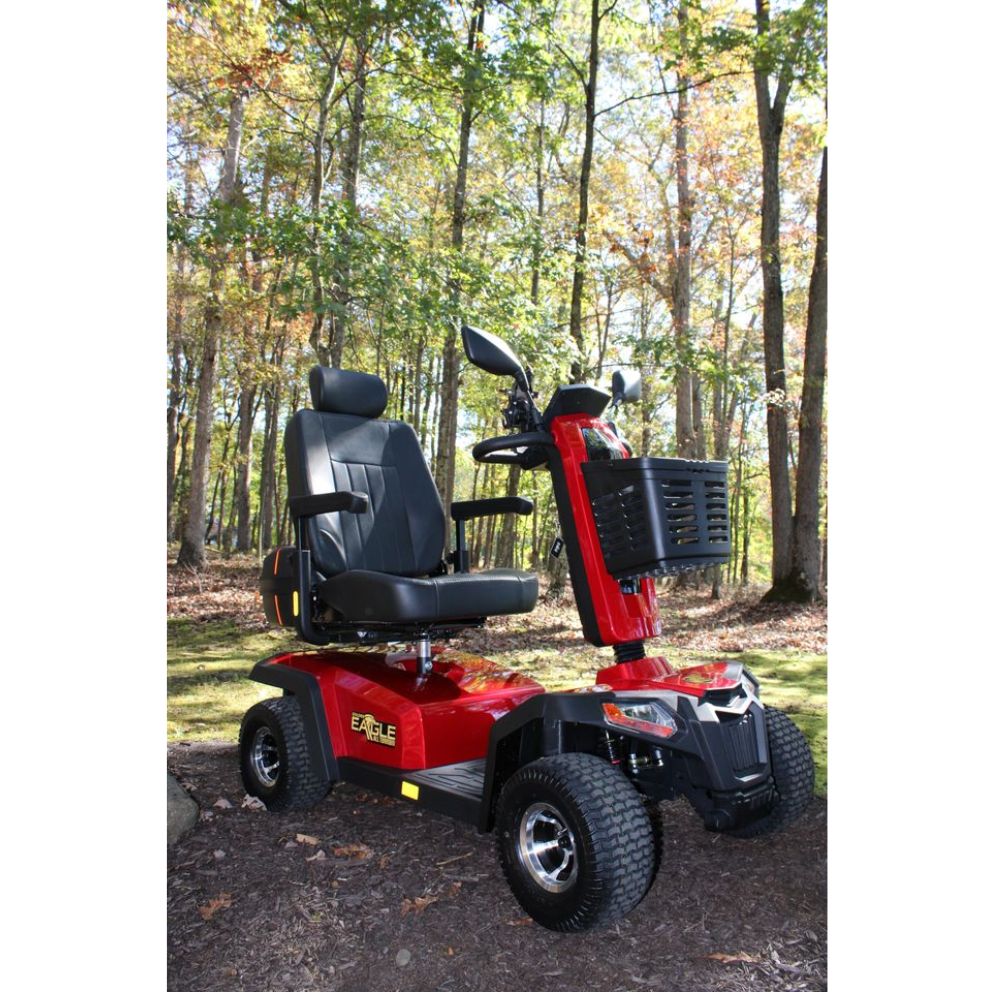 Eagle All-Terrain Scooter featuring a black seat and storage basket parked outdoors on grass, surrounded by tall trees with green and yellow leaves in daylight.