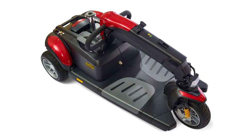 BuzzAround LX 3-Wheel Scooter in red and black, displayed from a high angle with the seat detached to show the platform, wheels, and steering column.