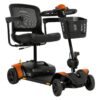 A compact mobility scooter with a four-wheel design, black seat, mesh backrest, and orange accents. It features a front basket and adjustable handlebars.