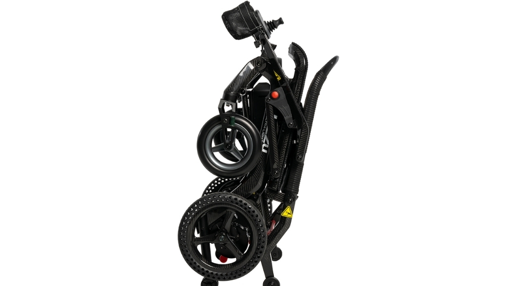 A Jazzy® Ultra Light Travel Power Wheelchair in black, with visible wheels and frame, is standing upright on a white background.