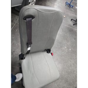 A Freedman 3PT Folding Seat in gray with an attached seatbelt is placed on a concrete workshop floor.