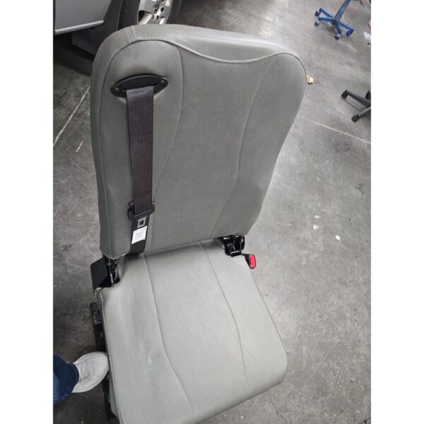 A Freedman 3PT Folding Seat in gray with an attached seatbelt is placed on a concrete workshop floor.