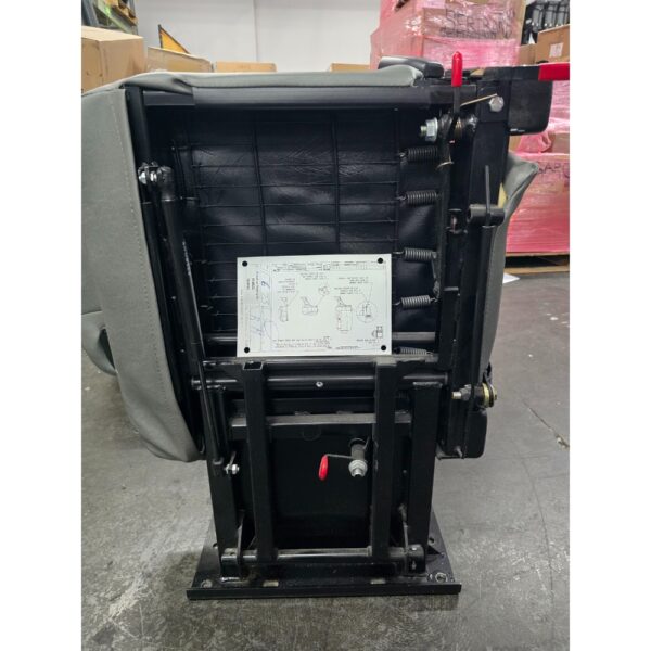 Underside view of a Freedman 3PT Folding Seat showing metal frame, springs, adjustment levers, and an attached instruction label with diagrams.