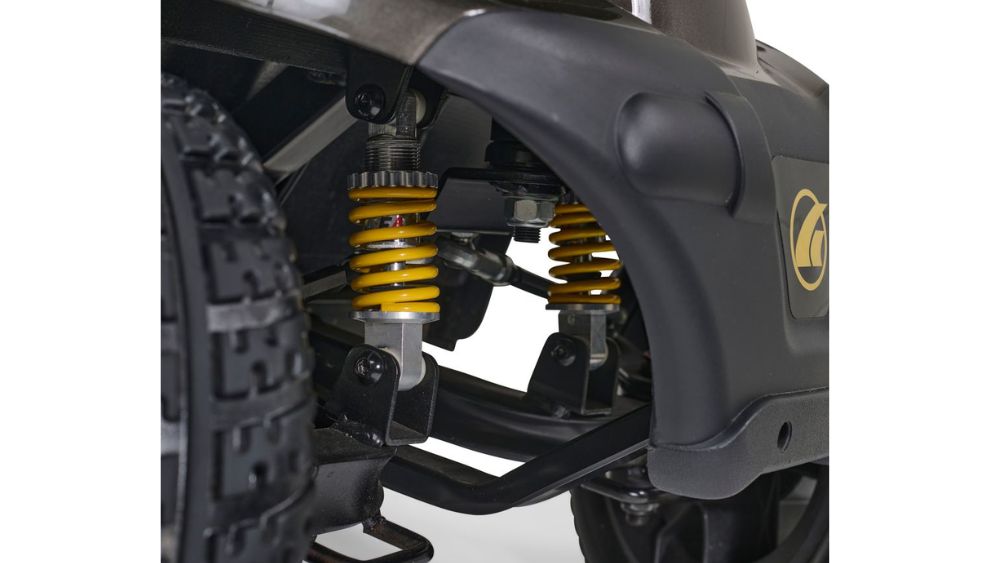 Close-up view of the Companion 4-Wheel Scooter’s suspension system, showcasing yellow coil springs, black components, and a portion of a rugged tire.