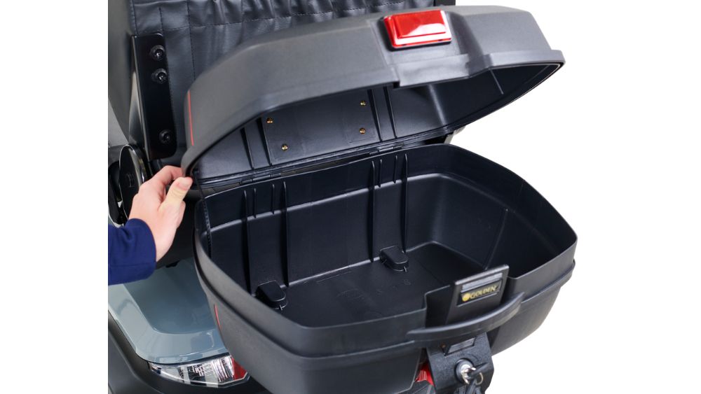 A person opens the empty rear storage compartment of an Eagle 4-Wheel Scooter, highlighting its spacious interior and durable black plastic construction.