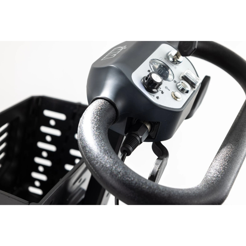 Close-up of a Monarch Mobility Genie Auto control tiller featuring a speed dial, horn button, battery indicator, and an attached front storage basket.