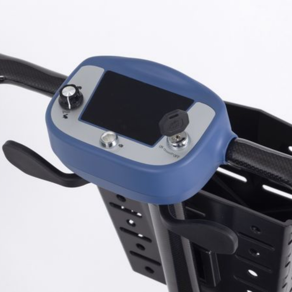 Control panel of a Monarch Mobility Genie Ultralight mobility scooter featuring a digital display, speed dial, key ignition, and a storage basket below.