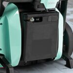 Close-up of an 11AH Lithium Battery for Go Go Super Portable, installed in a light teal mobility scooter or electric wheelchair, on a tiled floor.