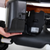 A hand is removing a rectangular battery pack from an Ally Power Wheelchair.