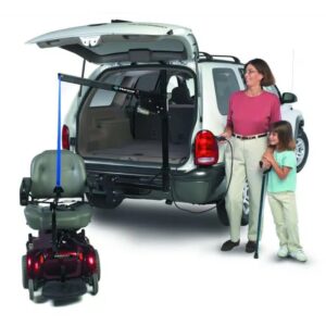 A woman stands beside a car with an open trunk, using a Harmar Universal Inside-Outside Lift (AL065) to load a mobility scooter. A child stands next to her, holding a cane.