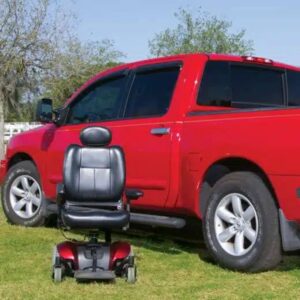 A red mobility scooter, compatible with the Harmar Tailgater 3-Axis Truck Lift (AL435T), is parked on grass beside a matching red pickup truck.