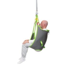 A bald man wearing grey and white clothing sits in a grey and green Human Care Basic Sling attached to an overhead lift system.