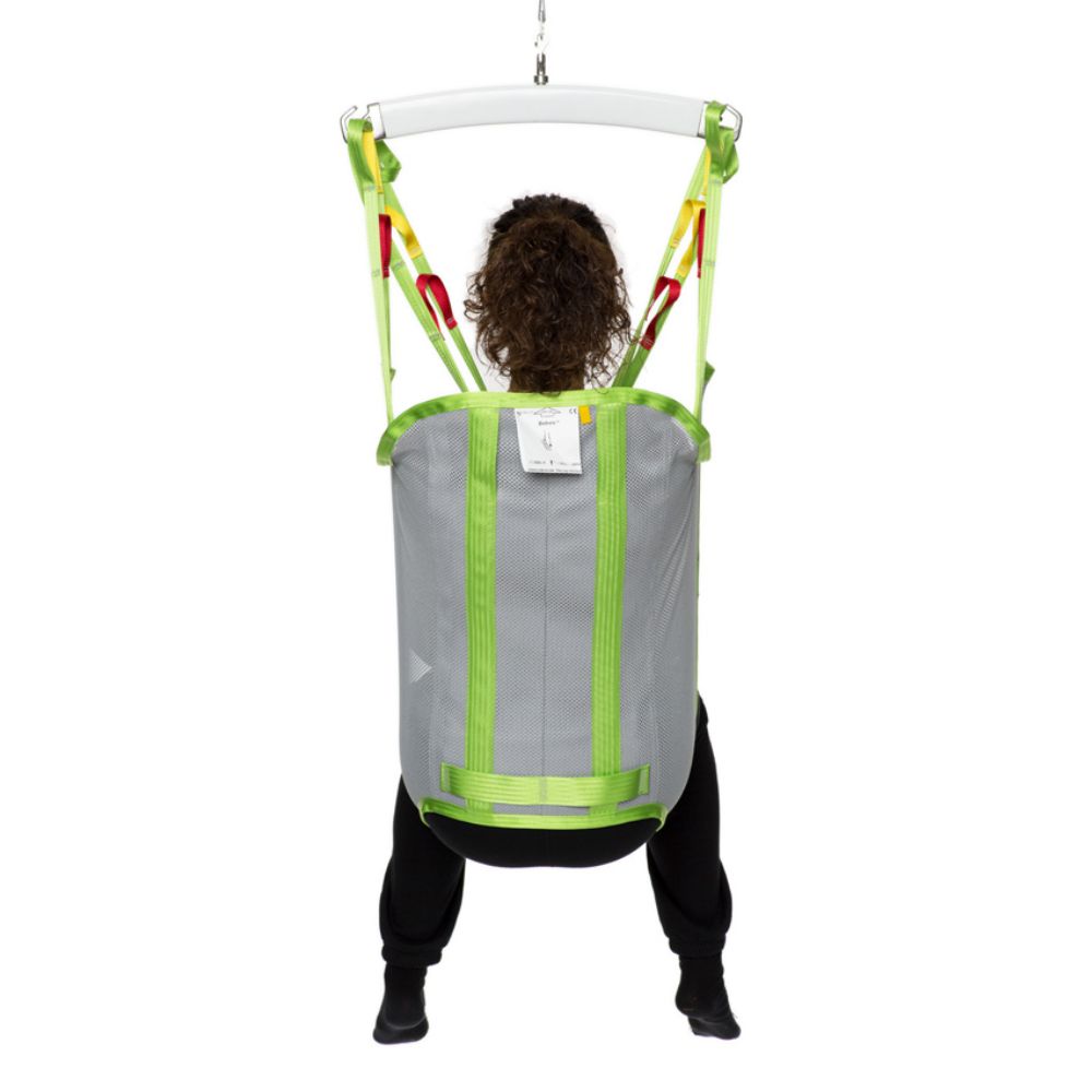 Person sitting in a gray and green Human Care Bath Sling-Polyester Net patient lift sling, lifted by straps attached to an overhead support, facing away from the camera.