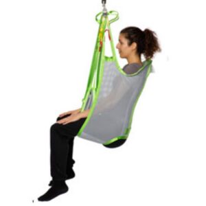 A person sits in a Human Care Bath Sling-Polyester Net patient lift sling, suspended from a hoist, with legs hanging down and arms resting on the sides.