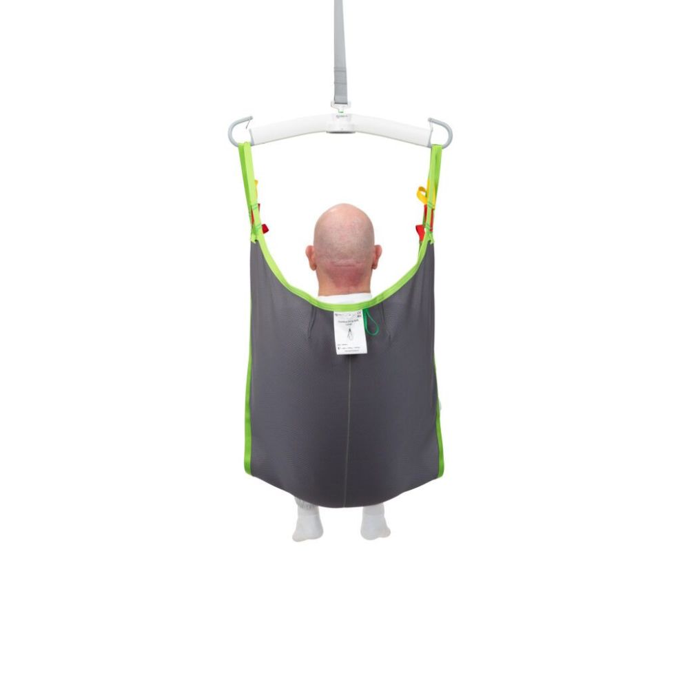 A bald person is seated in a gray and green fabric Human Care Comfort Sling attached to a patient lift, viewed from behind, against a white background.