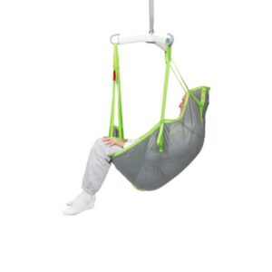 A person sits in a gray and green Human Care Full Body Sling, suspended from a white overhead bar, against a plain white background.
