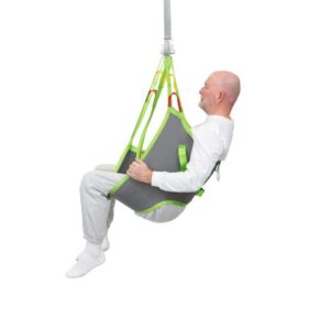 An older man sits in a gray and green Human Care Low Basic Sling, suspended from a ceiling lift, against a white background.