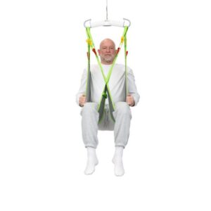 An older man in white clothing sits in a green Human Care Low Basic Sling, suspended in midair against a plain white background.