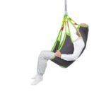 A person sits in a gray and green Human Care Silhouette Sling, suspended in the air against a white background.
