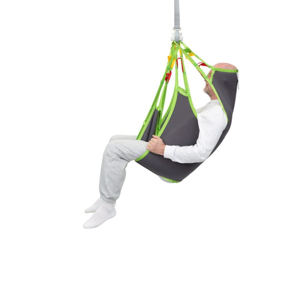 A person sits in a gray and green Human Care Silhouette Sling, suspended in the air against a white background.