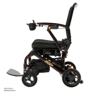 The Jazzy Carbon 27 Power Wheelchair is a lightweight, foldable electric wheelchair with a black cushioned seat, armrests, storage pouch, and front basket, pictured in side profile on a white background.
