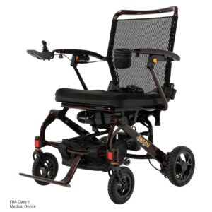 The Jazzy Carbon 27 Power Wheelchair features a black frame, mesh back, padded seat, joystick armrest control, footrest, four wheels, and Jazzy branding on the side.