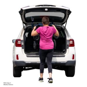 A woman in athletic wear loads a Jazzy Carbon 27 Power Wheelchair into the trunk of a white SUV with the rear hatch open.