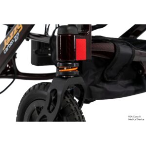 Close-up of the front wheel and suspension of the Jazzy Carbon 27 Power Wheelchair, highlighting detailed components and a portion of its storage bag.