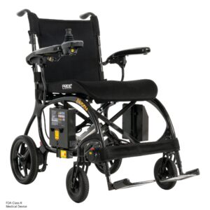 The Jazzy Carbon 27X Power Wheelchair is a black, lightweight electric wheelchair with joystick control, padded seat, mesh backrest, footrests, rear and front wheels, and a visible FDA Class II medical device label.