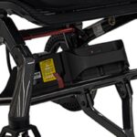 Close-up of the 10AH Lithium Battery for Jazzy Ultra Light installed beneath the seat, highlighting safety labels, indicator lights, and part of the frame.