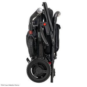 The Jazzy Carbon Travel Power Wheelchair is shown in its fully folded, upright position with visible black wheels and lightweight frame components.