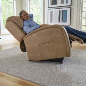 A man reclines in an EZ Sleeper with Twilight Lift Chair, tan color, on a gray rug in a bright living room with abstract art on the wall.