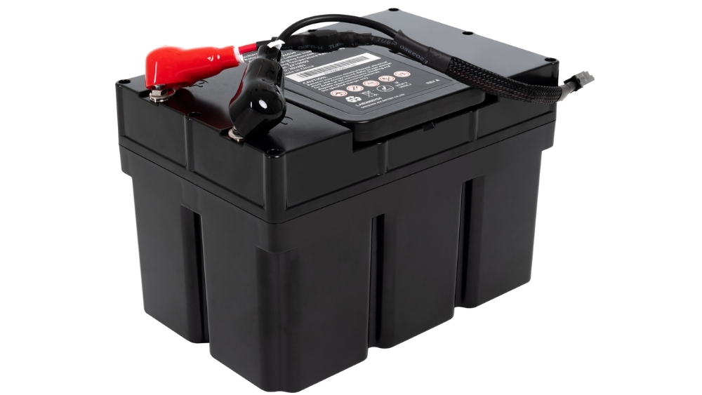 A black rectangular Jazzy EVO 613 Li Power Wheelchair battery with red and black terminals on top and a label featuring safety symbols and specifications.