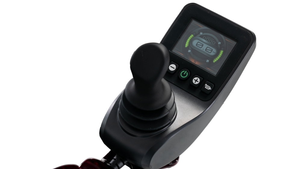 A close-up of a joystick controller with a digital display screen and several buttons, designed for operating the Jazzy Carbon Travel Power Wheelchair.