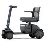 A compact, modern WHILL Model R mobility scooter with three wheels, a mesh backrest, armrests, and a front basket, shown from the side on a white background.